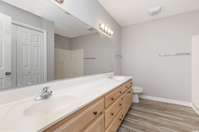 bathroom featuring wood-type flooring, walk in shower, vanity, and toilet