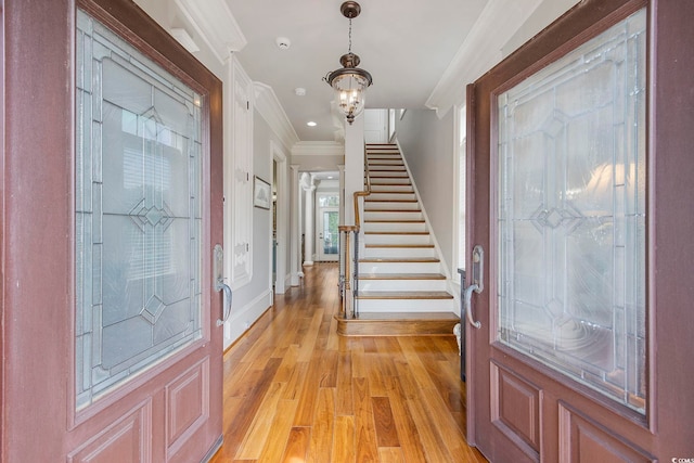 entrance foyer featuring a notable chandelier, light wood-type flooring, and crown molding