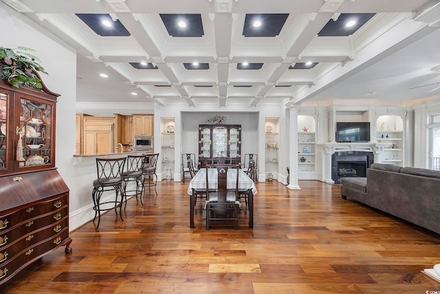 interior space featuring wood-type flooring, ceiling fan, beamed ceiling, and ornate columns