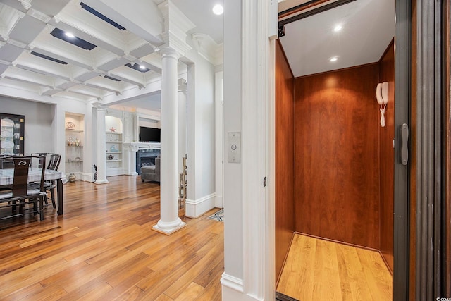 interior space with elevator, light hardwood / wood-style flooring, built in features, and ornate columns