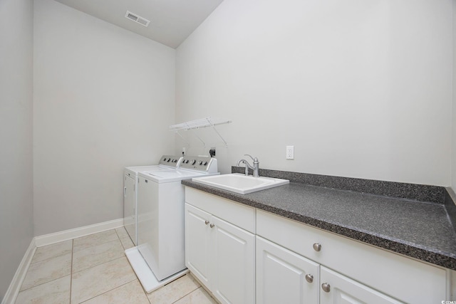 laundry area with light tile patterned floors, sink, washing machine and clothes dryer, and cabinets