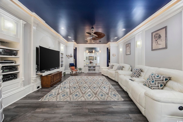 living room featuring ceiling fan with notable chandelier, built in features, dark wood-type flooring, and crown molding