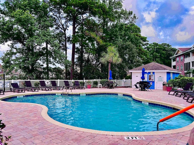 view of pool with a patio and an outbuilding