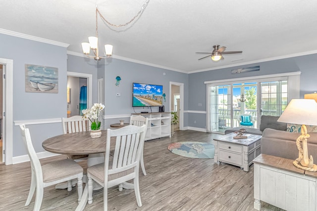 dining space with crown molding, ceiling fan with notable chandelier, and light hardwood / wood-style flooring