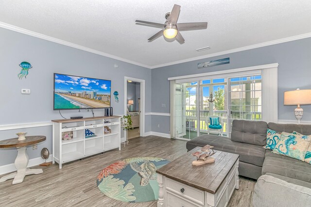 living room with ornamental molding, light hardwood / wood-style flooring, a textured ceiling, and ceiling fan