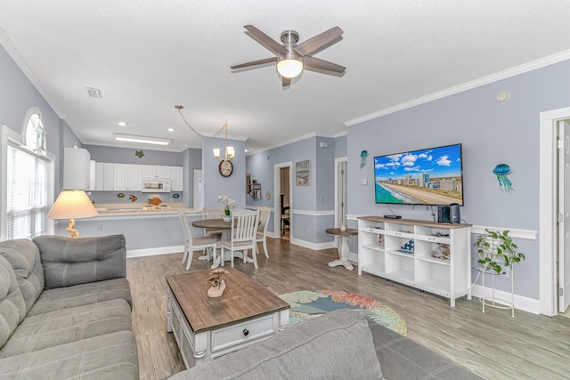 living room with ceiling fan, crown molding, and light hardwood / wood-style flooring