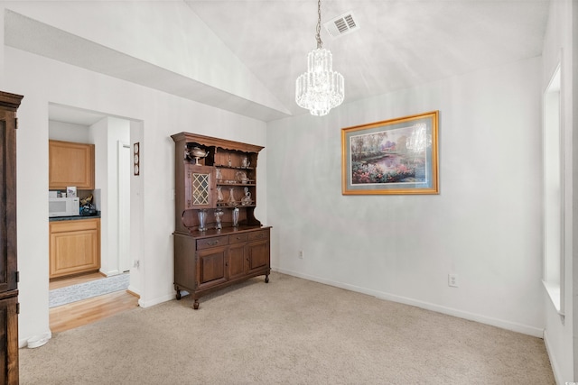 dining area featuring vaulted ceiling, a chandelier, and light carpet