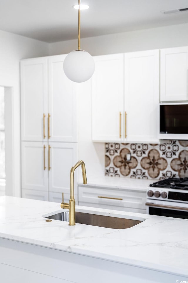 kitchen with a sink, stainless steel range with gas cooktop, and white cabinetry