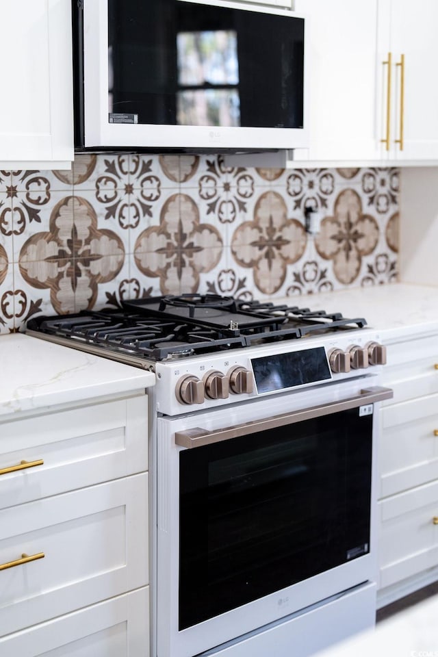 kitchen featuring light stone counters, decorative backsplash, white cabinetry, and gas range oven