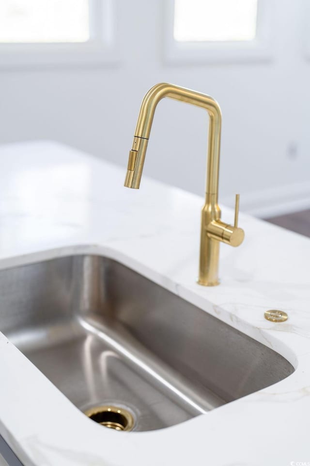 interior details with a sink and light stone counters