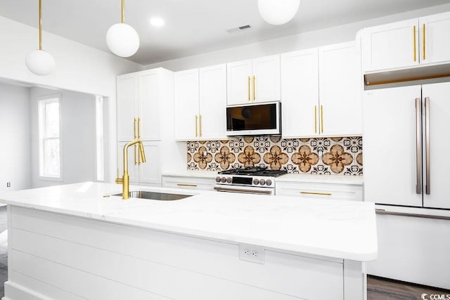 kitchen featuring visible vents, a center island with sink, a sink, white appliances, and white cabinets