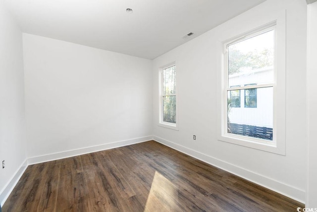 spare room featuring visible vents, dark wood-type flooring, and baseboards