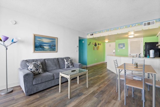 living area with visible vents, a textured ceiling, and wood finished floors