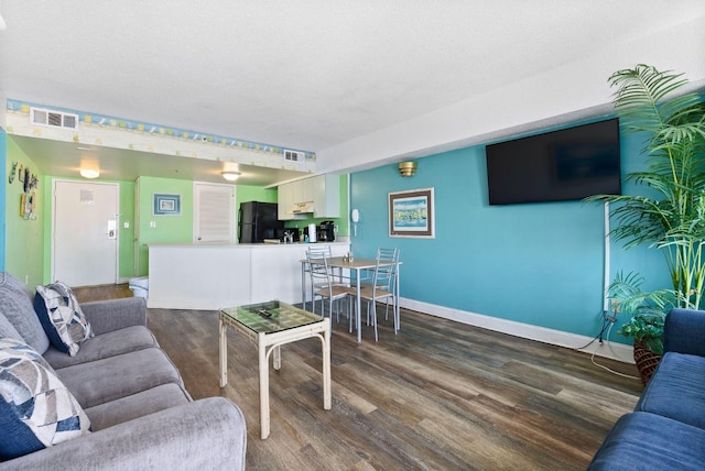 living area with dark wood-type flooring, baseboards, and visible vents