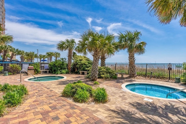 view of swimming pool with a patio, a community hot tub, and fence