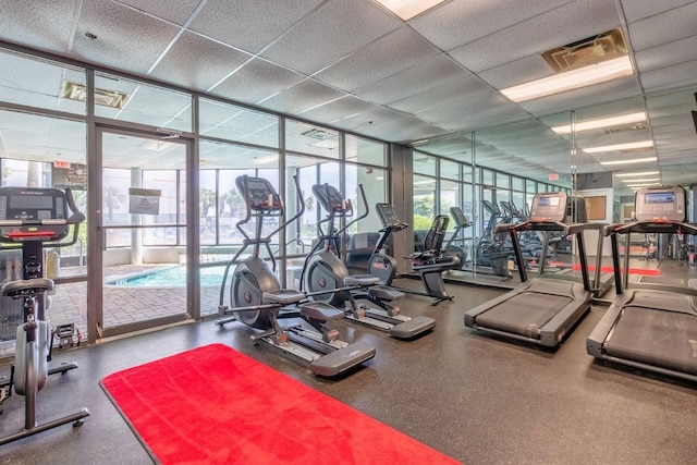 workout area featuring visible vents, a paneled ceiling, and expansive windows