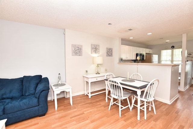 dining space featuring a textured ceiling and light wood-type flooring