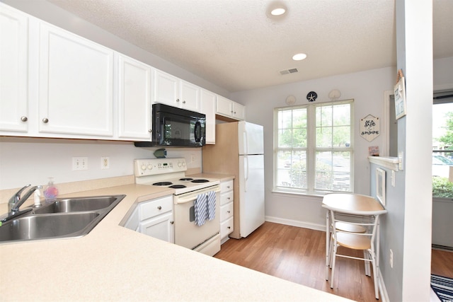 kitchen with white cabinets, light hardwood / wood-style flooring, white appliances, and sink