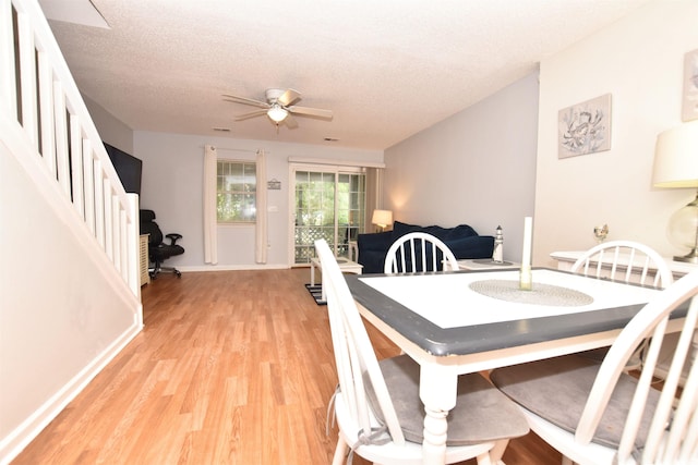 dining area with light wood-type flooring, ceiling fan, and a textured ceiling