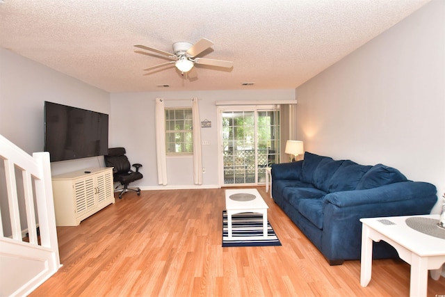 living room with light hardwood / wood-style floors, a textured ceiling, and ceiling fan