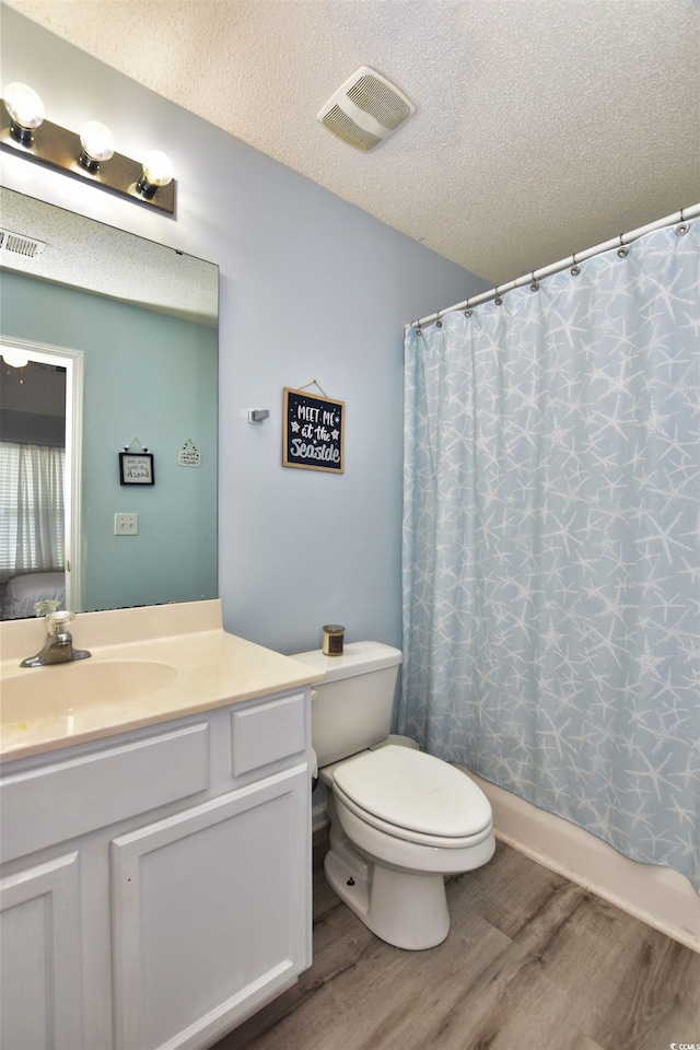 bathroom with toilet, hardwood / wood-style floors, vanity, and a textured ceiling