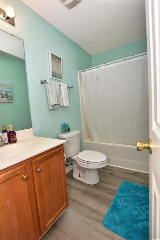 full bathroom with shower / bath combination with curtain, a textured ceiling, toilet, vanity, and hardwood / wood-style flooring