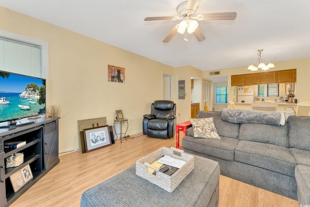 living room with ceiling fan with notable chandelier and light hardwood / wood-style flooring