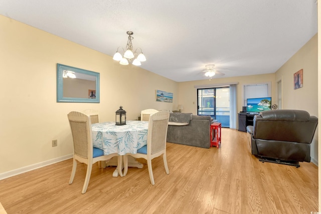 dining room featuring ceiling fan with notable chandelier, a textured ceiling, and light wood-type flooring