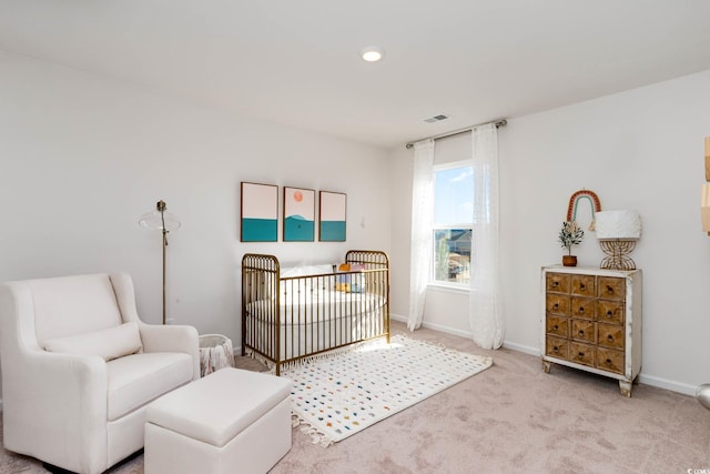 carpeted bedroom featuring a nursery area