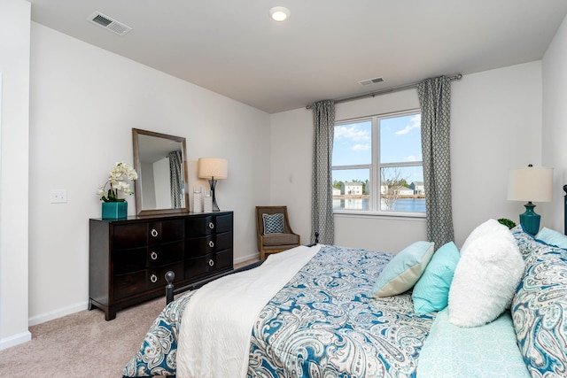 bedroom featuring light carpet and a water view