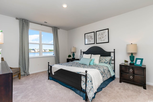 bedroom featuring a water view and light colored carpet