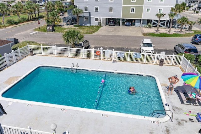 community pool with a patio area and fence