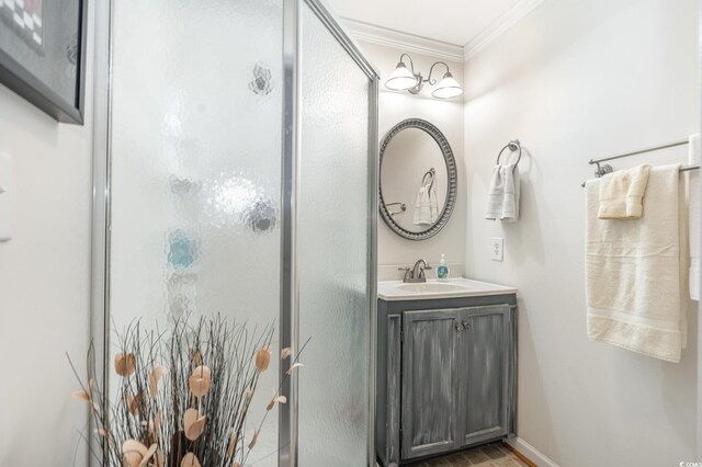 bathroom with crown molding, hardwood / wood-style floors, vanity, and walk in shower