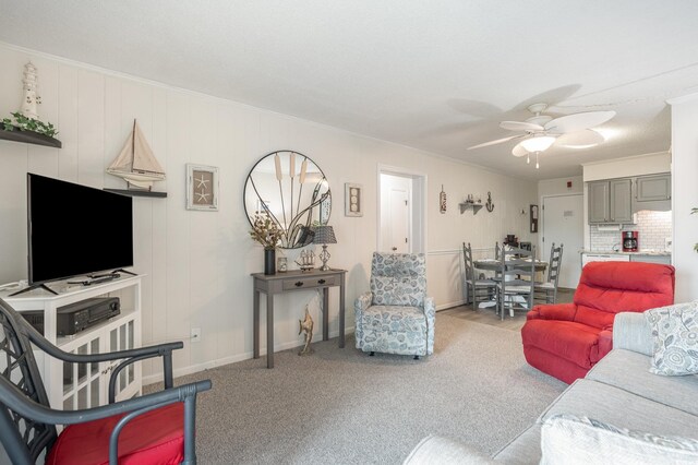 carpeted living room with ceiling fan and crown molding