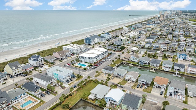 drone / aerial view featuring a view of the beach, a water view, and a residential view