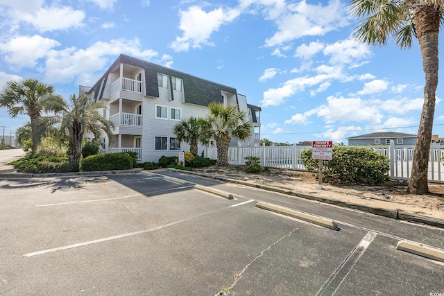 view of building exterior with uncovered parking and fence