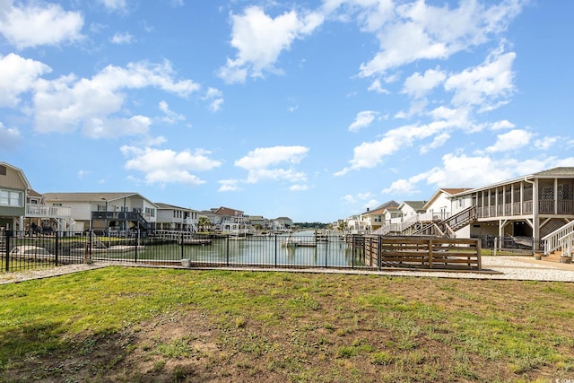 view of yard featuring a residential view, a sunroom, a water view, and fence