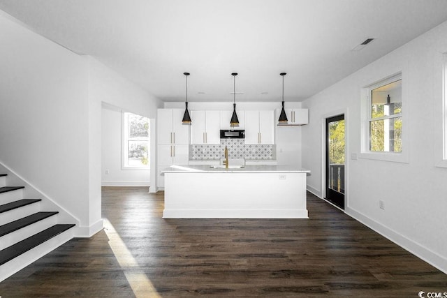 kitchen featuring dark wood-type flooring, a sink, tasteful backsplash, white cabinetry, and black microwave