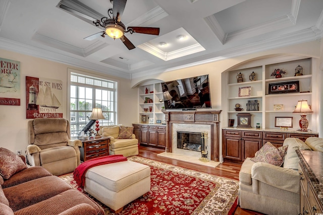 living room with a high end fireplace, coffered ceiling, crown molding, built in features, and light hardwood / wood-style floors