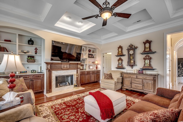 living room with coffered ceiling, built in features, a high end fireplace, and light hardwood / wood-style flooring