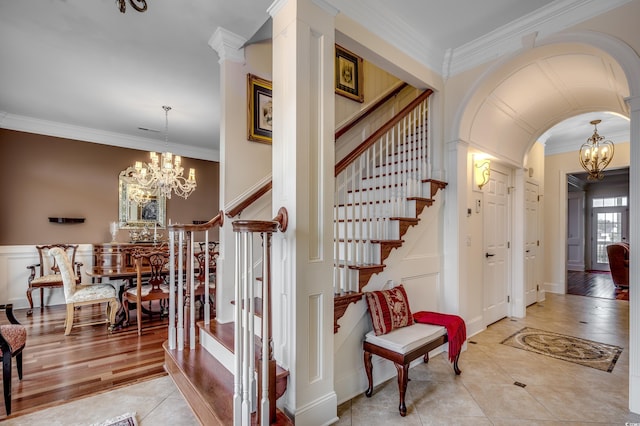 stairs with tile patterned flooring, crown molding, and a notable chandelier