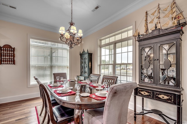 dining room with wood-type flooring, ornamental molding, and an inviting chandelier