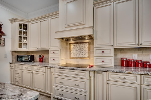 kitchen with cream cabinets, black electric stovetop, ornamental molding, tasteful backsplash, and light stone counters