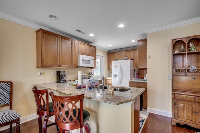 kitchen with white appliances, dark wood-type flooring, ornamental molding, a kitchen bar, and kitchen peninsula