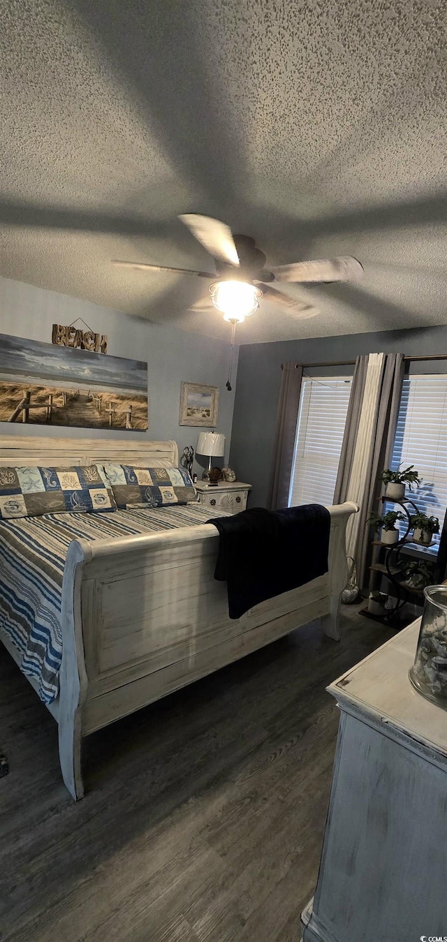 bedroom with dark hardwood / wood-style flooring, ceiling fan, multiple windows, and a textured ceiling