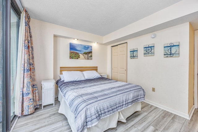 bedroom featuring a textured ceiling and light hardwood / wood-style floors