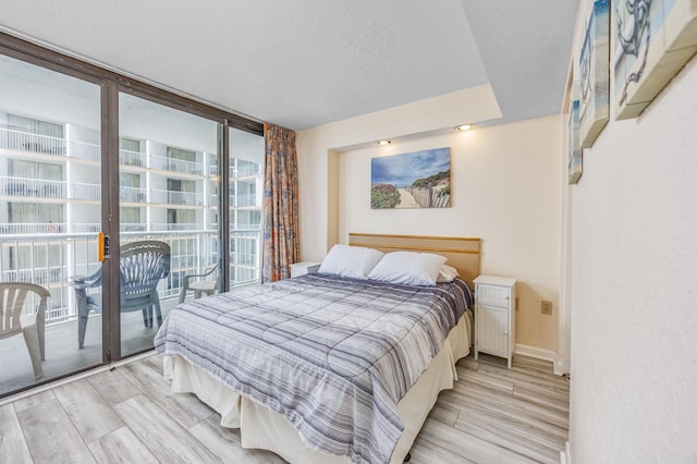 bedroom with access to outside, floor to ceiling windows, and a textured ceiling