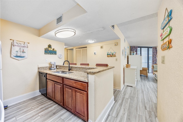 kitchen with dishwashing machine, sink, light hardwood / wood-style floors, kitchen peninsula, and light stone countertops