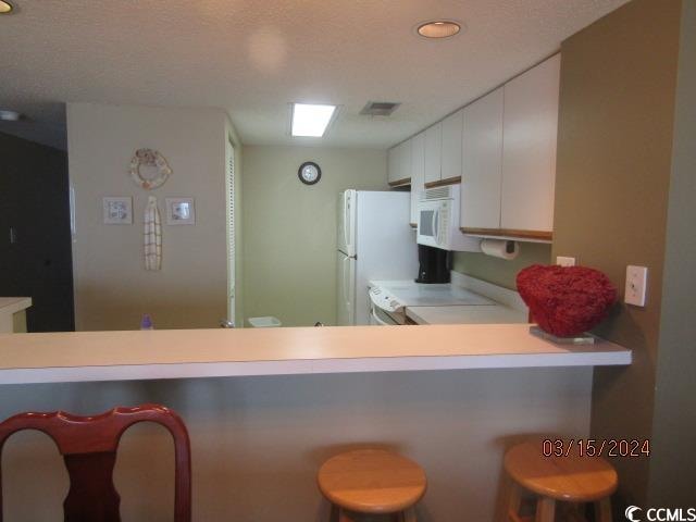 kitchen featuring white cabinetry, a textured ceiling, and a kitchen breakfast bar