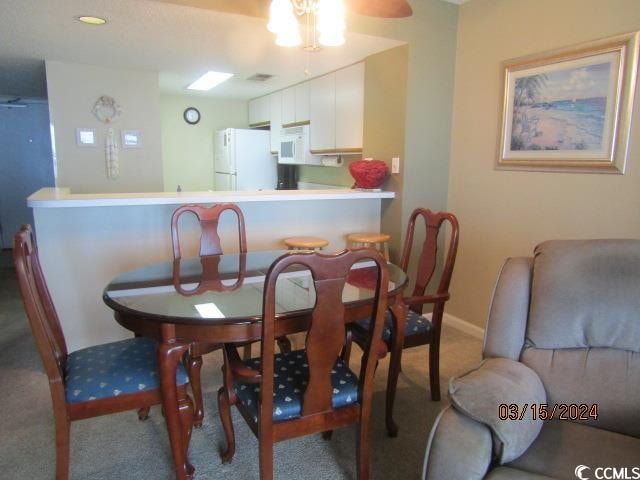 carpeted dining area with ceiling fan